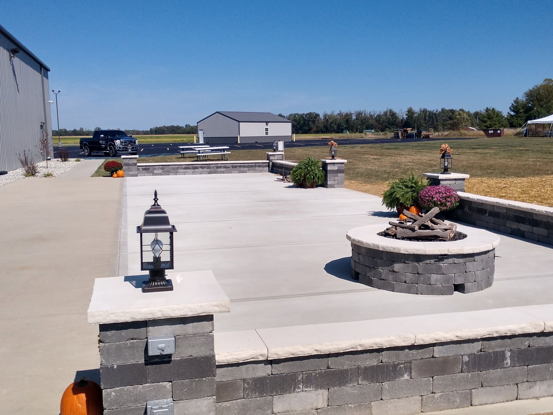 Finished concrete patio space featuring built-in stone walls and entry pillars equipped with lantern light fixtures