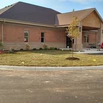 Front landscaping area of a brick property featuring a concrete curb and a freshly strawed lawn
