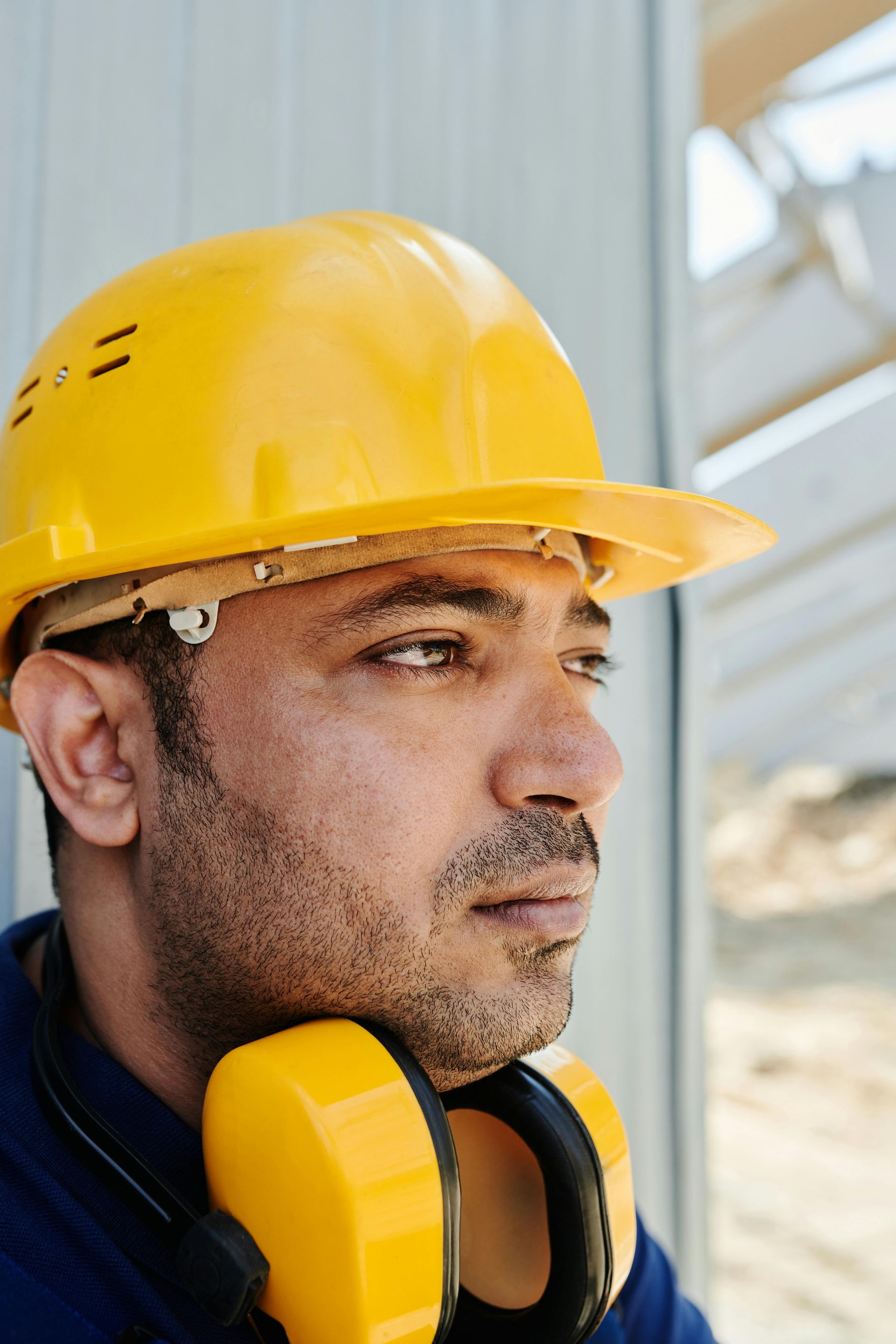 Forte Safe Construction worker wearing a yellow hard hat and earmuffs, looking off to the side.
