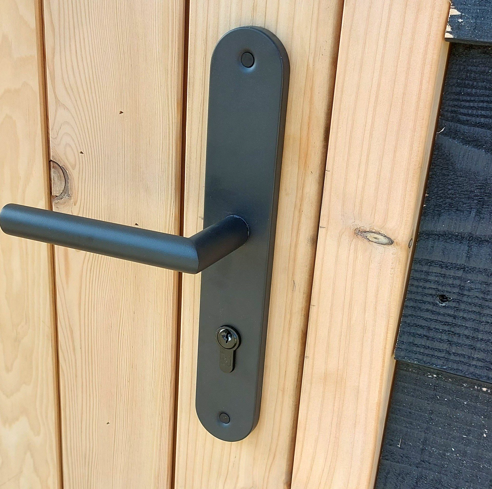 Een zwarte deurkruk op een houten deur