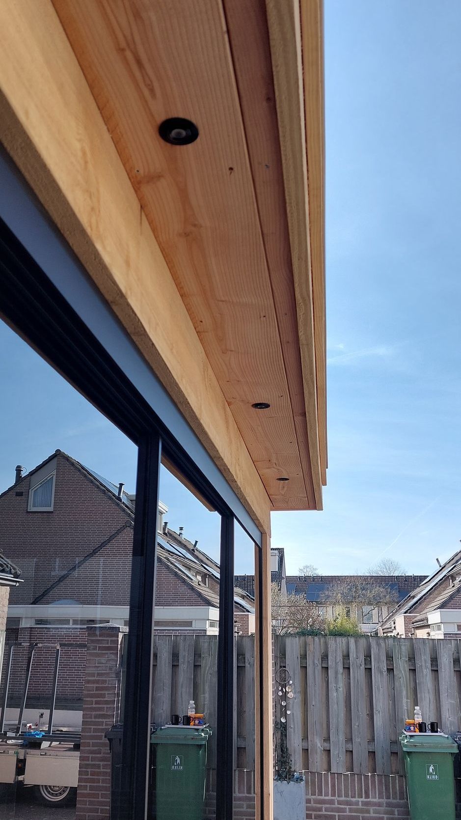 Een huis met een houten dak en glazen schuifdeuren.