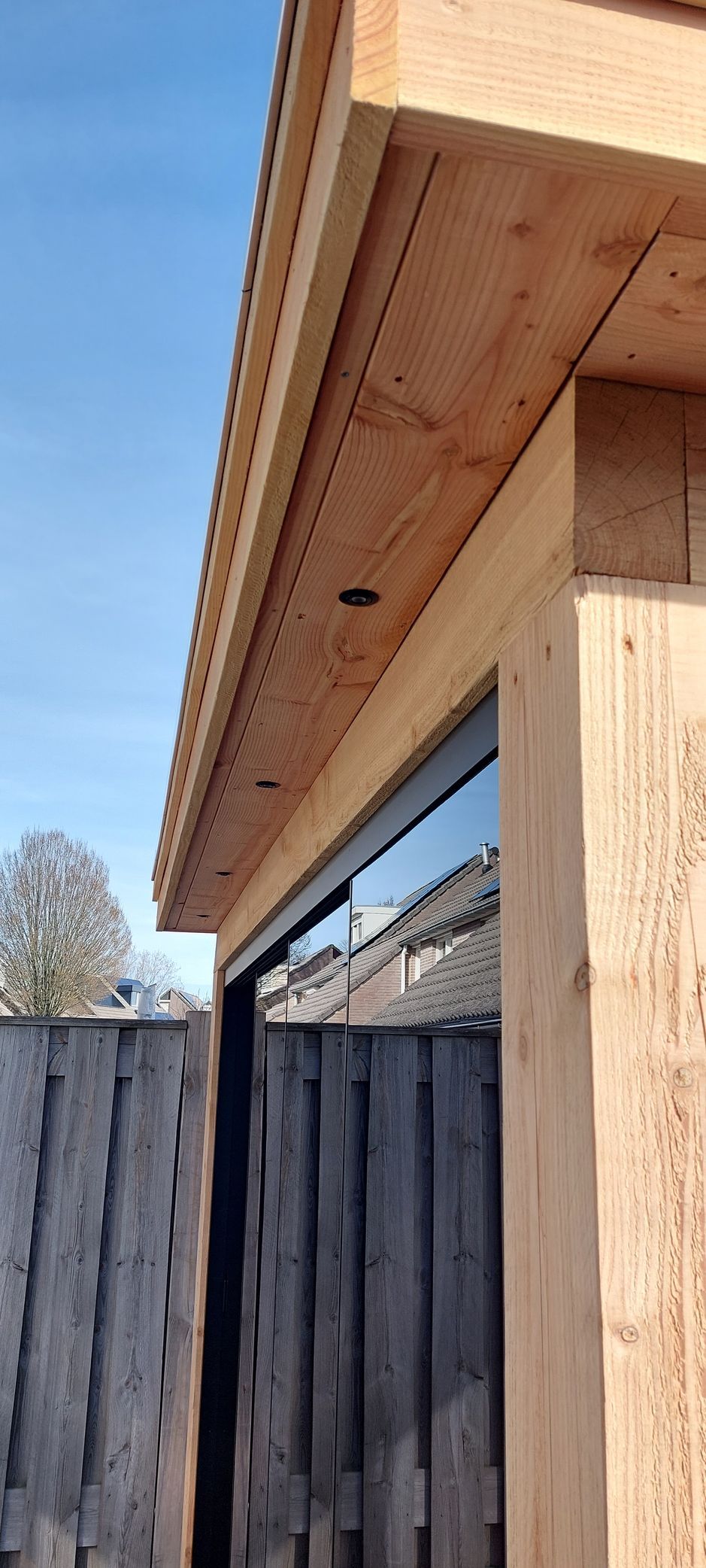 Een houten gebouw met een glazen schuifdeur en een houten hek op de achtergrond.