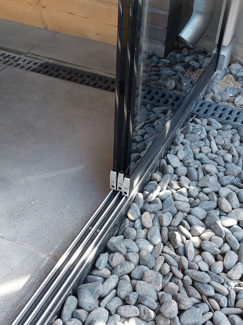 Een glazen schuifdeur staat bovenop een stapel stenen.