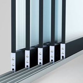 Een close-up van een meerdelig schuifdeursysteem van glas, met metalen frames, glaspanelen en rails.