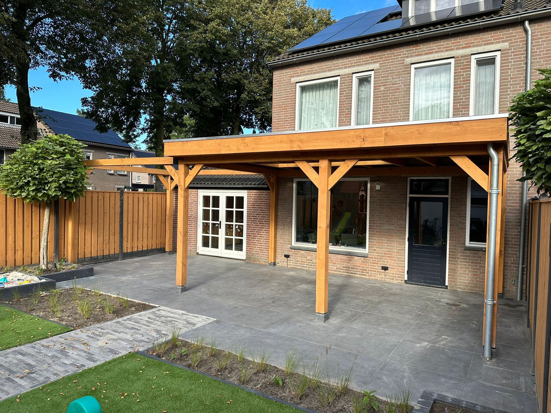Een huis met een houten pergola ervoor