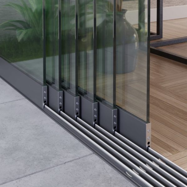 Een close-up van een glazen schuifdeursysteem met meerdere panelen en grijze metalen frames, die over rails op de vloer schuift.