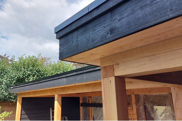 Er wordt een houten huis met een zwart dak gebouwd.