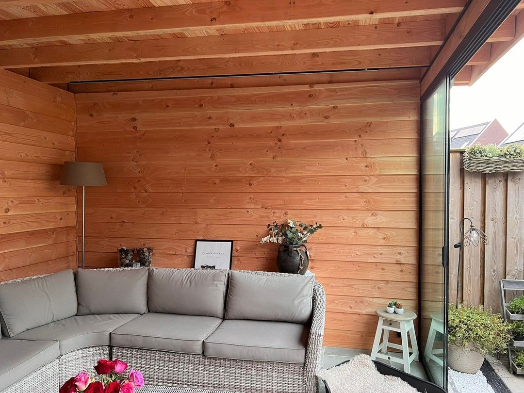 Een woonkamer met een bank en glazen schuifdeuren.