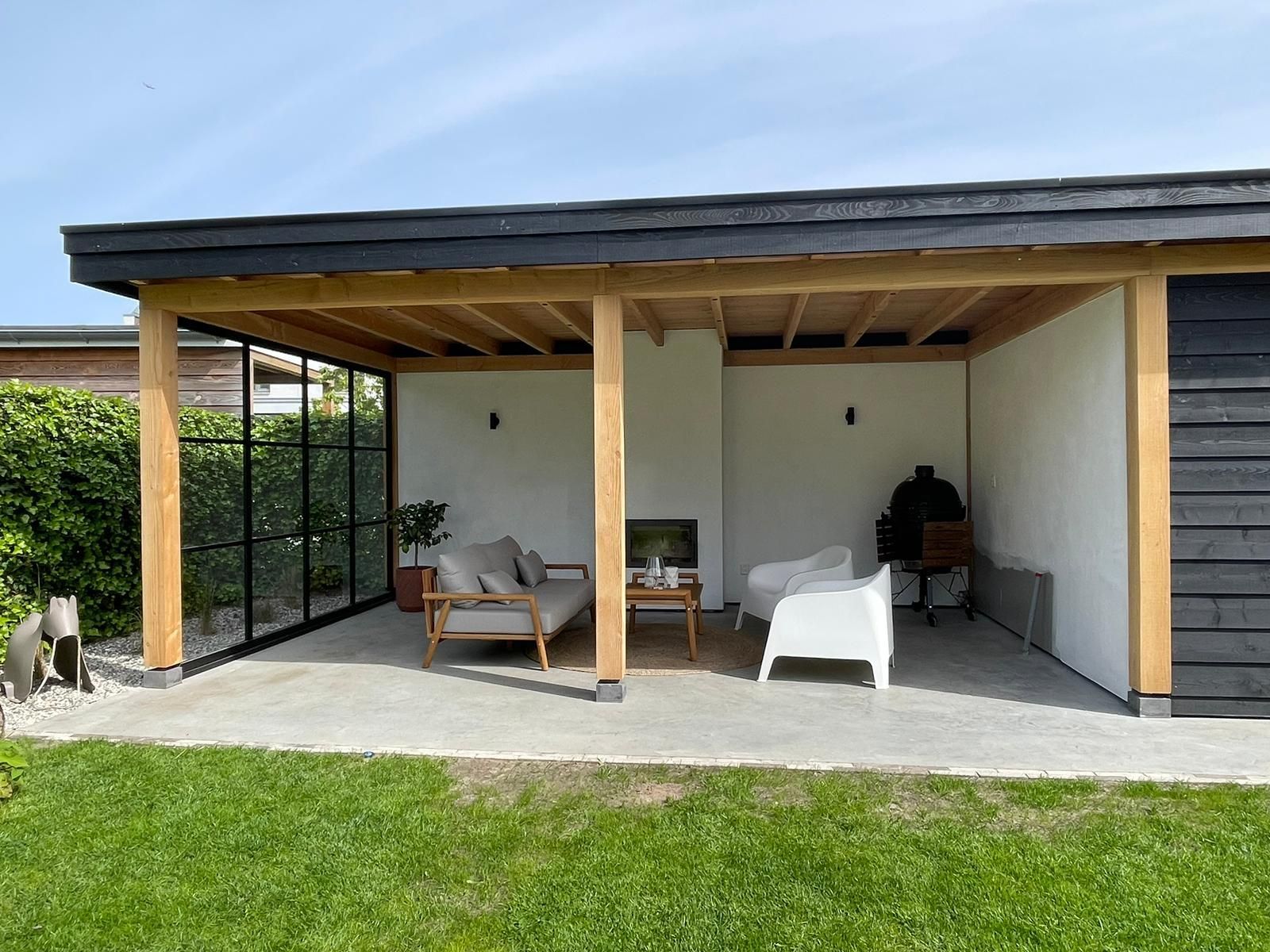 Een overdekt terras met een bank, stoelen en een open haard.