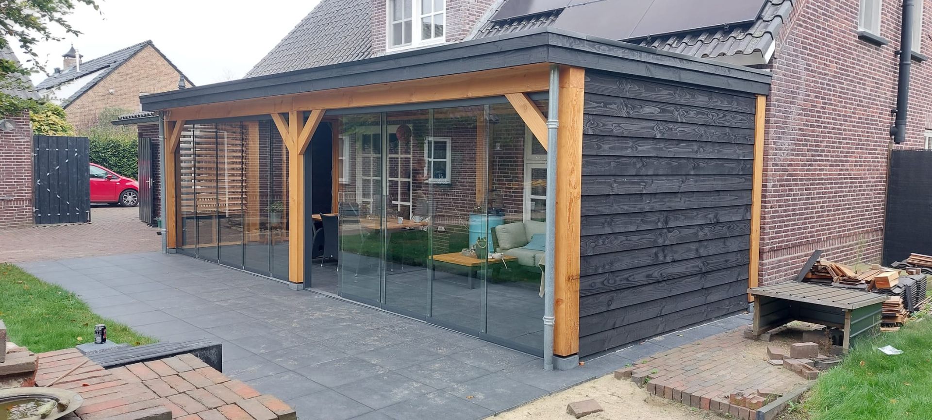 Een huis met een groot overdekt terras met glazen schuifdeuren.