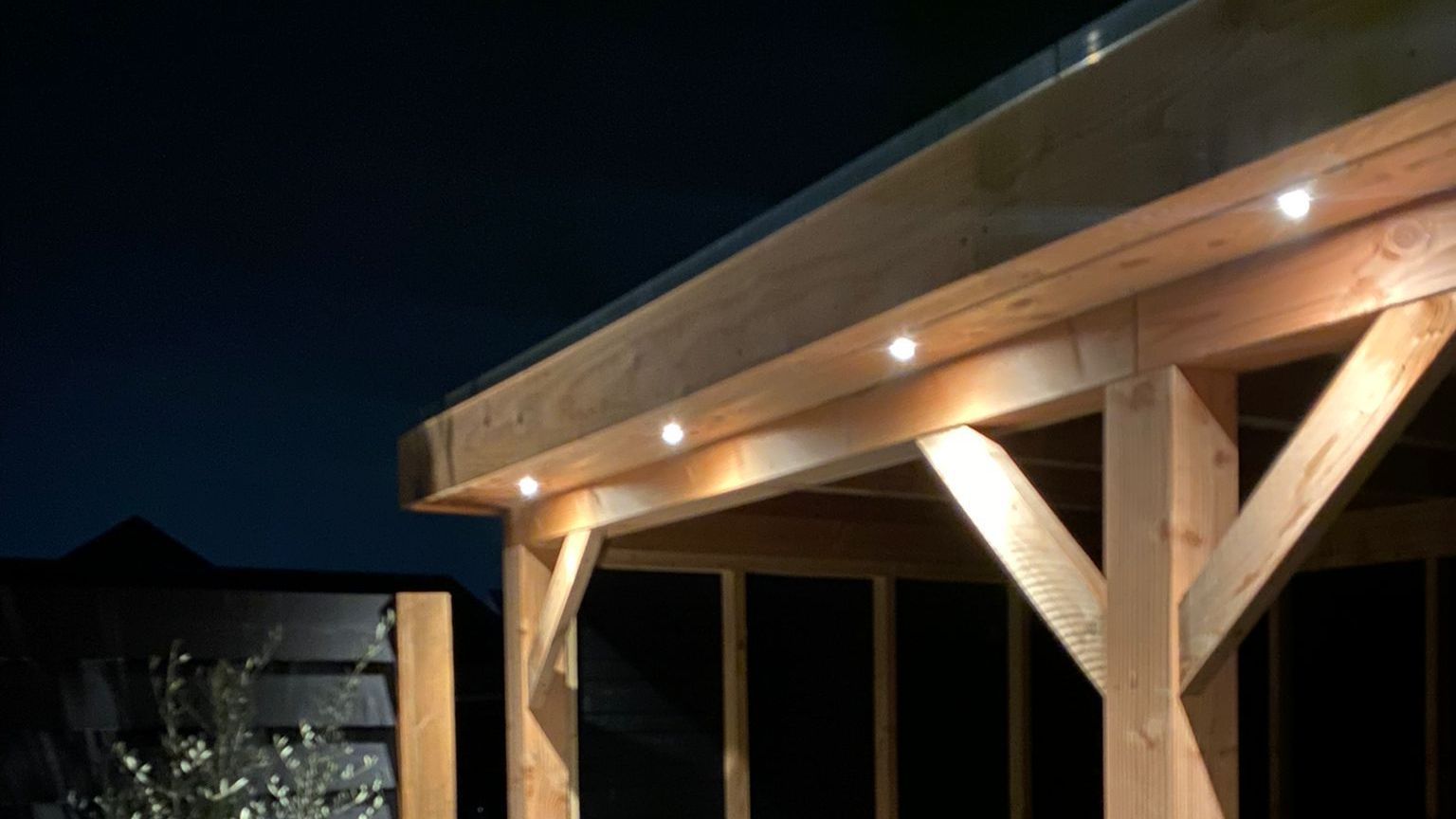 Een houten constructie met verlichting erop wordt 's nachts verlicht.