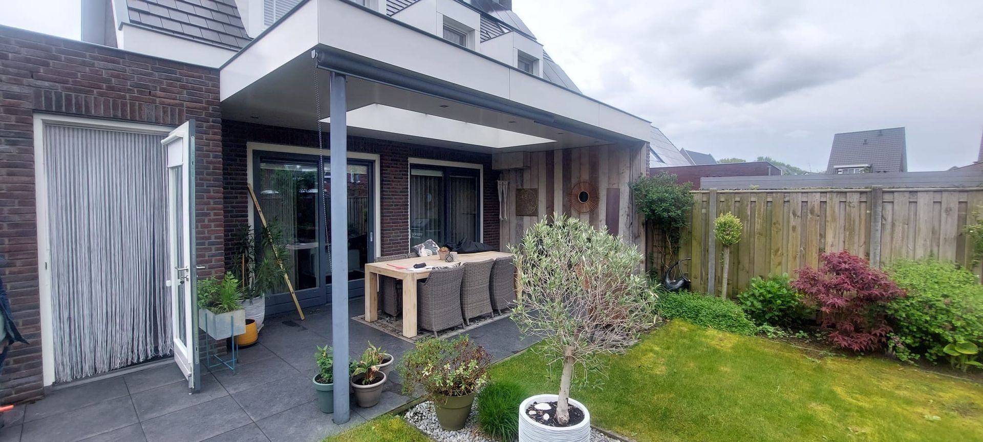Er is een terras met een tafel en stoelen in de achtertuin van een huis.