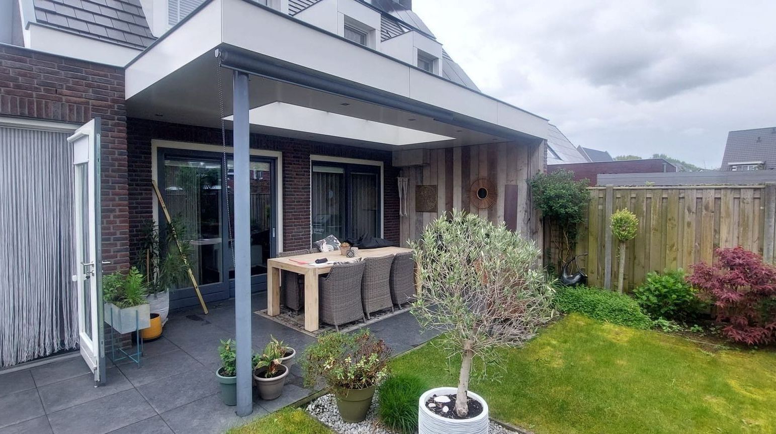 Een terras met een tafel en stoelen in de achtertuin van een huis.