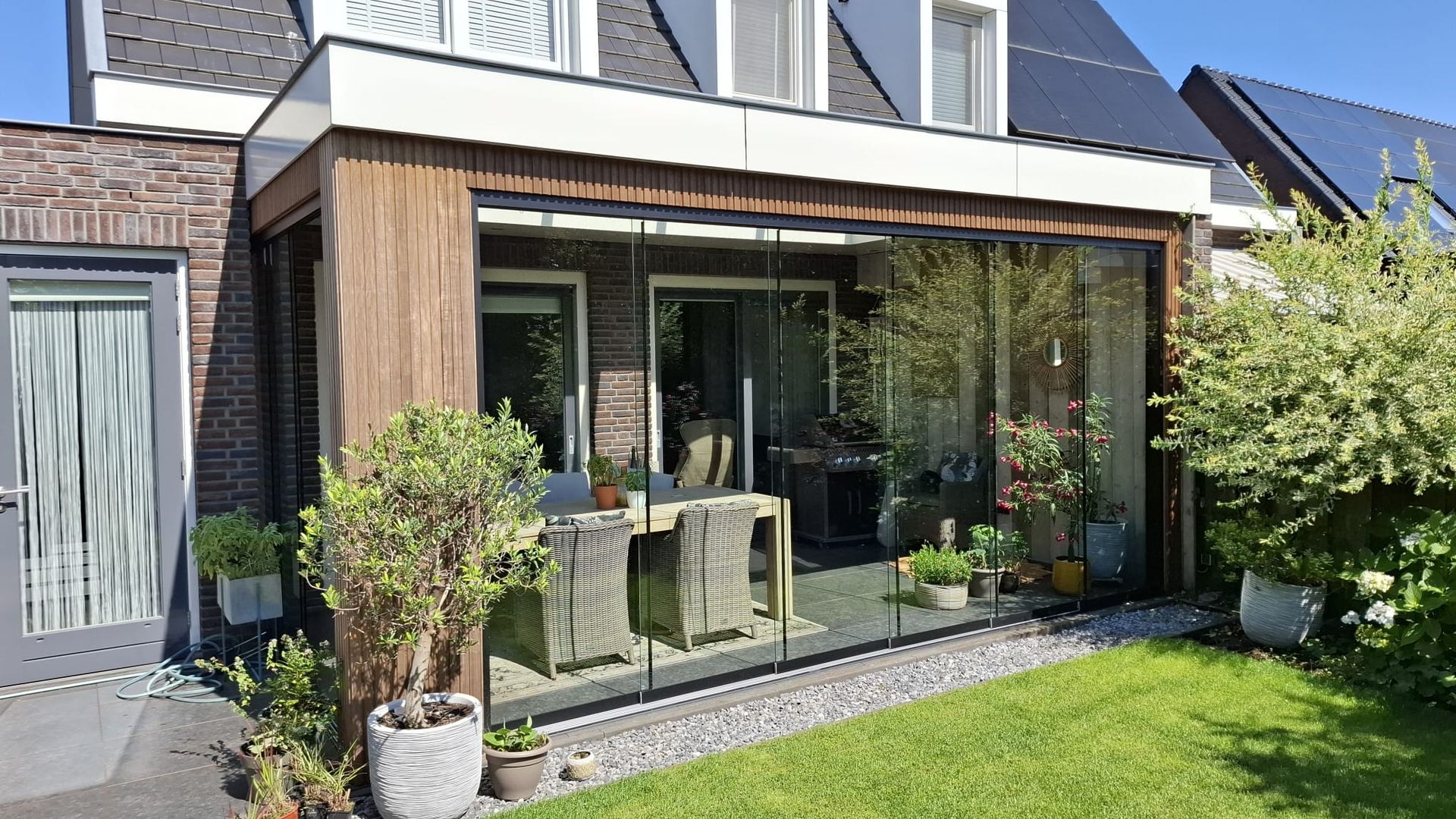 Een huis met een terras met een tafel en stoelen ervoor.