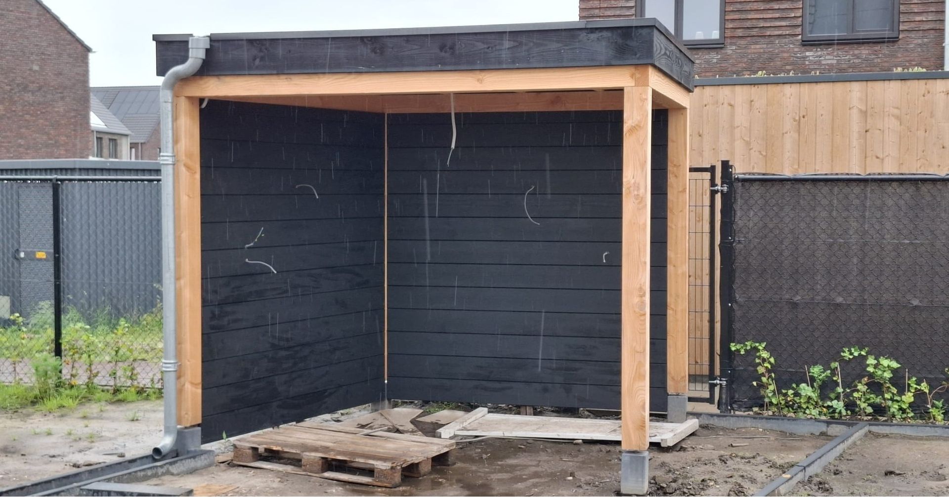 Er wordt een houten constructie gebouwd in de achtertuin van een huis.