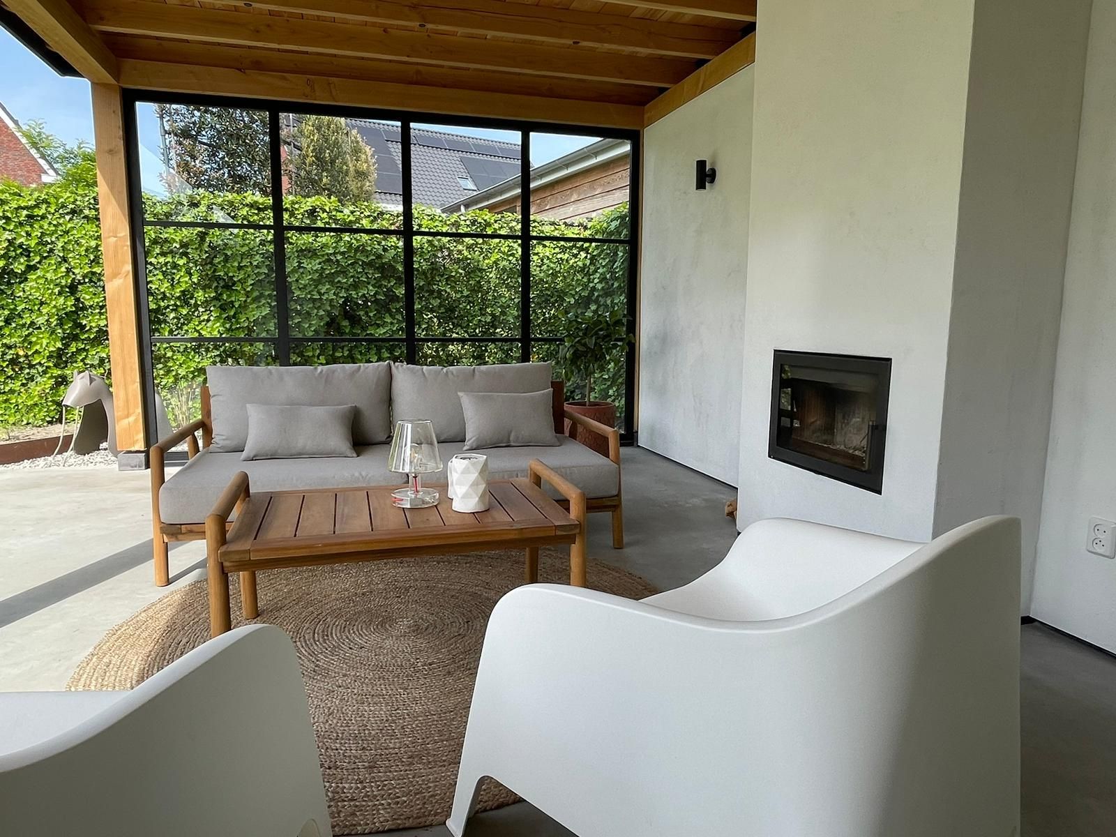 Een woonkamer met een bank, stoelen, tafel en open haard.