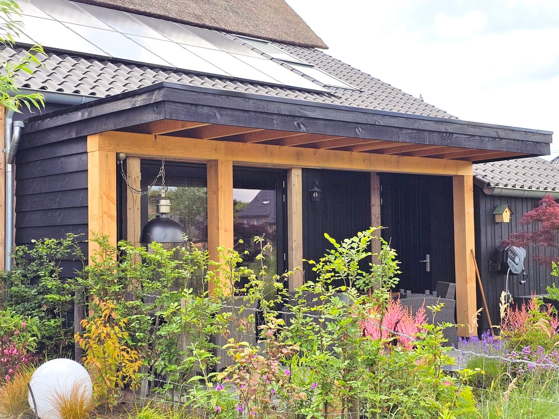 Een huis met een houten veranda en een rieten dak