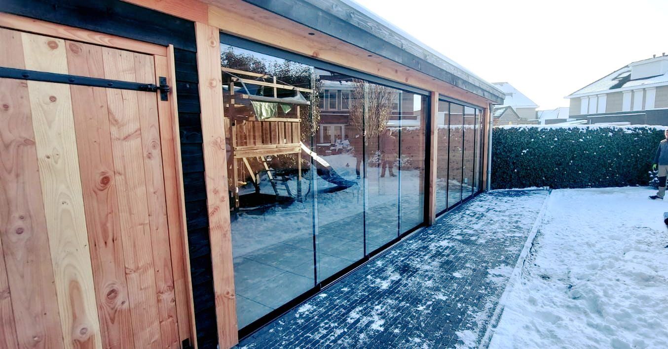 Een houten gebouw met glazen schuifdeuren in de sneeuw.