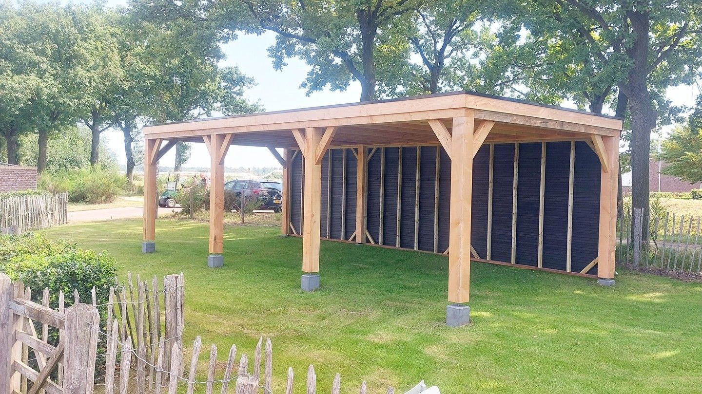 Een houten constructie staat midden in een weelderig groen veld.