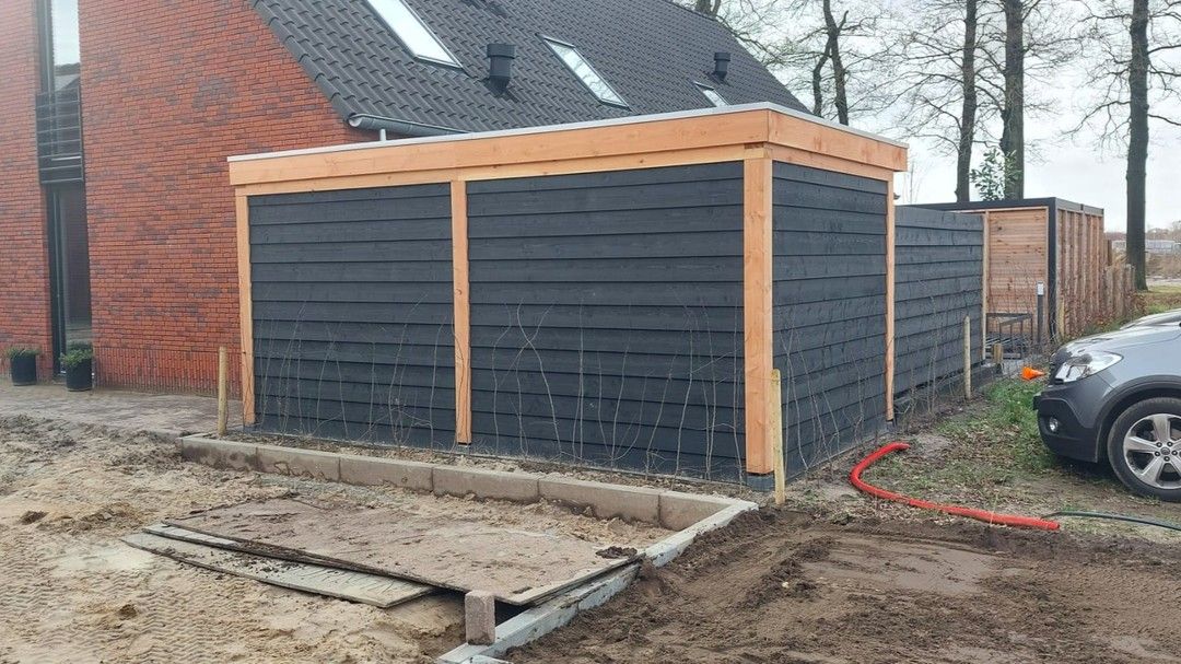 Een auto staat geparkeerd voor een houten schuur.