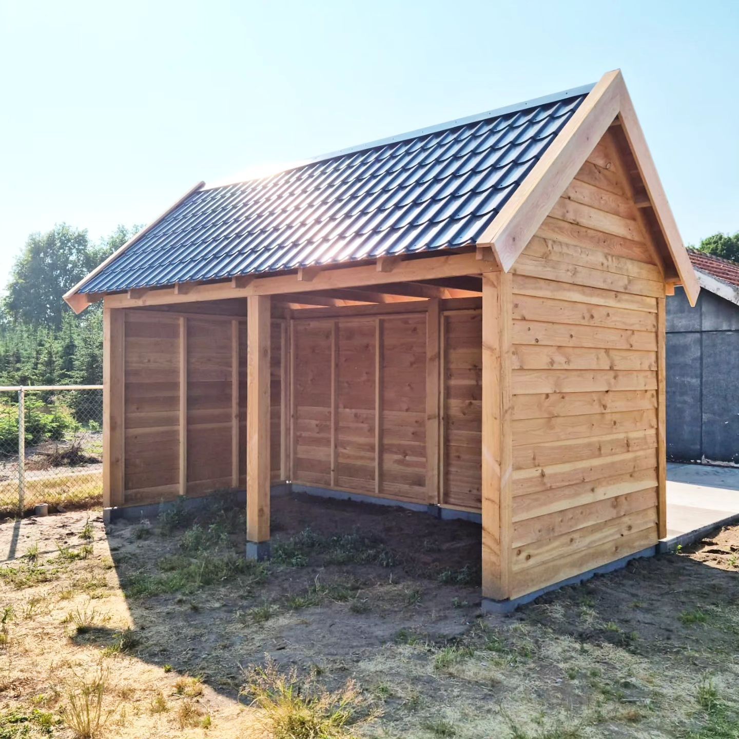 Een klein houten schuurtje met een zwart dak