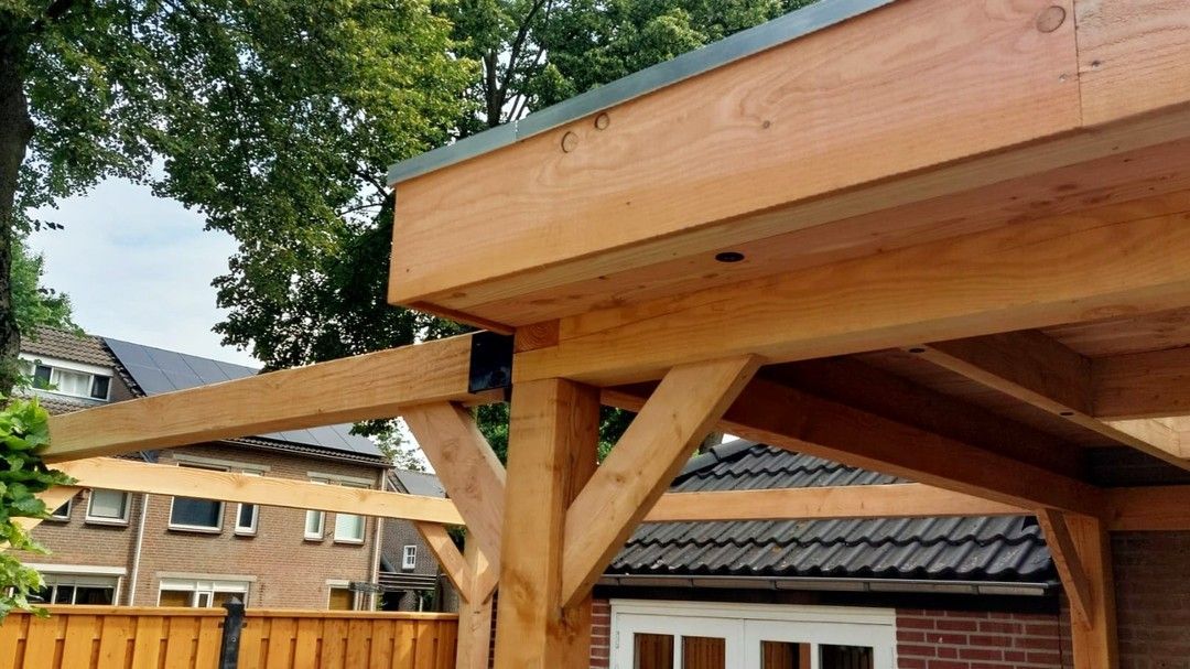Een houten constructie staat voor een bakstenen huis.