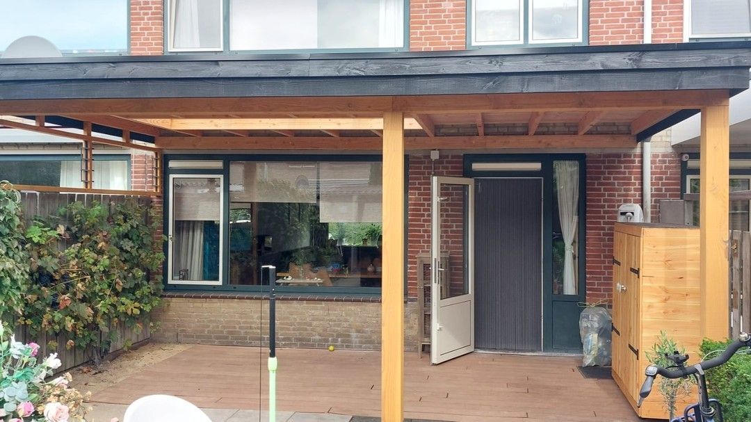 Een bakstenen huis met een houten veranda ervoor.