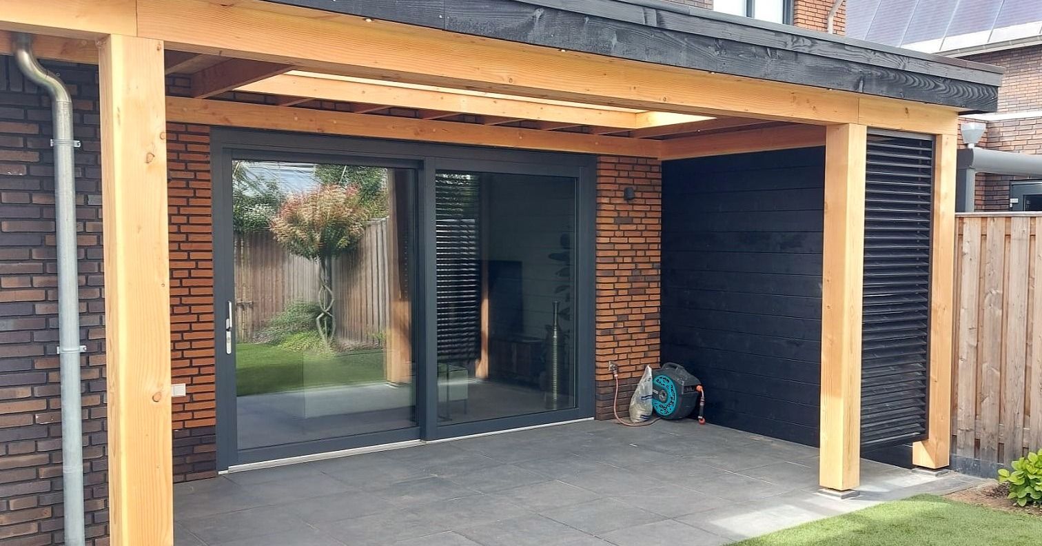 Een huis met een houten veranda en glazen schuifdeuren.