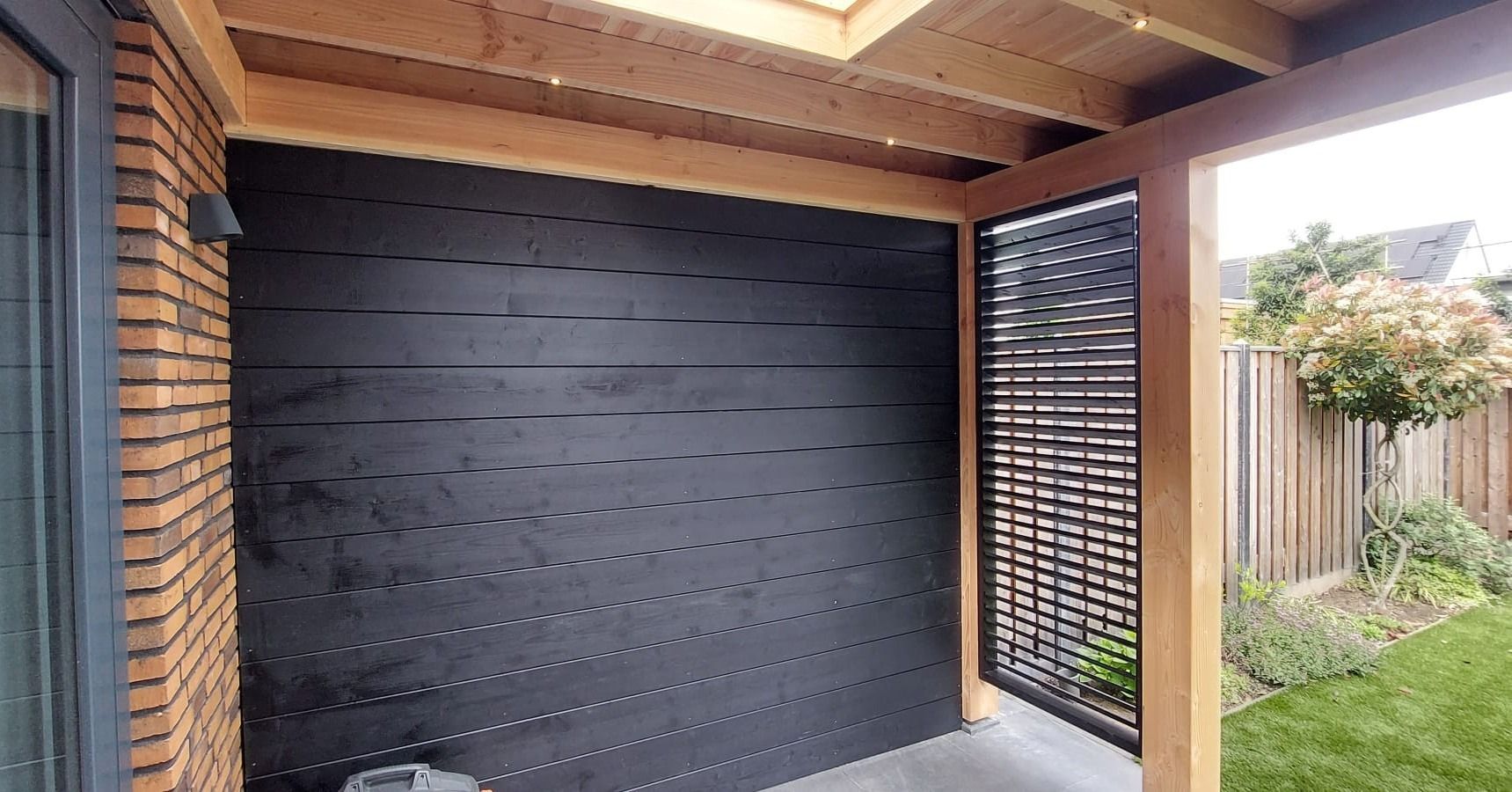 Een bakstenen gebouw met een houten dak en een zwarte muur.