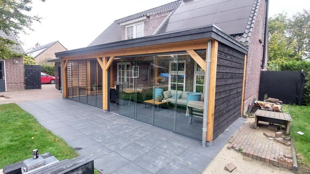 Een huis met een groot overdekt terras met glazen schuifdeuren.