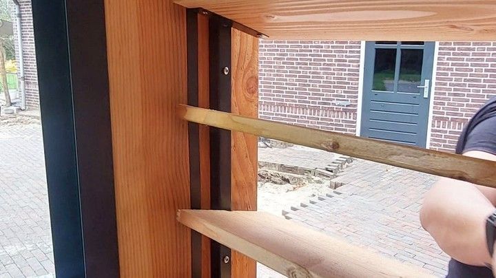 Iemand werkt aan een houten constructie voor een bakstenen gebouw.
