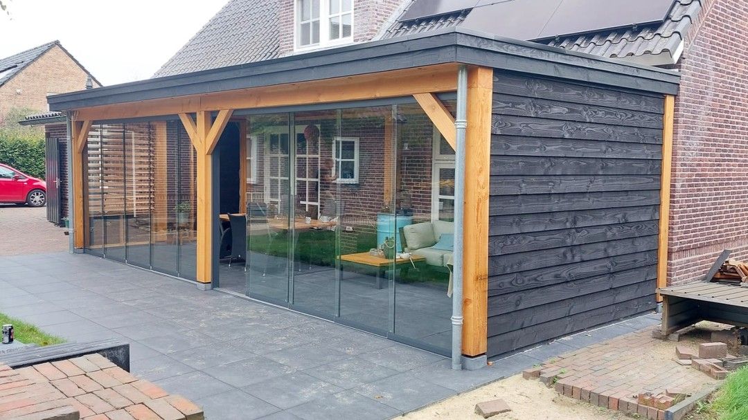 Een huis met een grote veranda met glazen schuifdeuren.