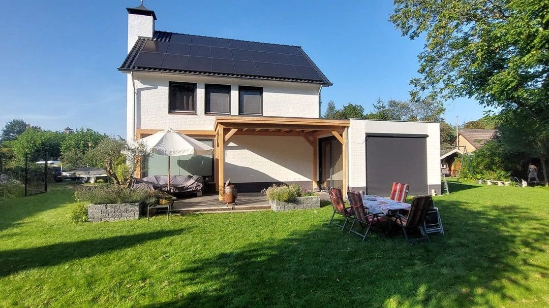 Een huis met een tafel en stoelen ervoor.