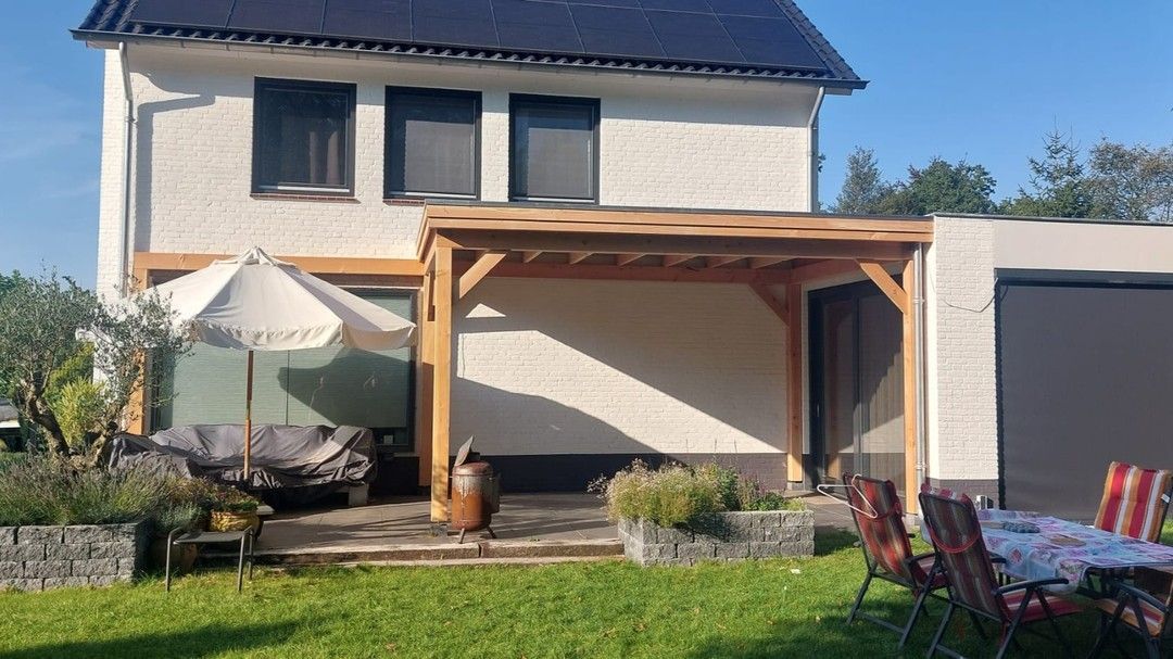 Er staat een tafel en stoelen in de achtertuin van een huis.