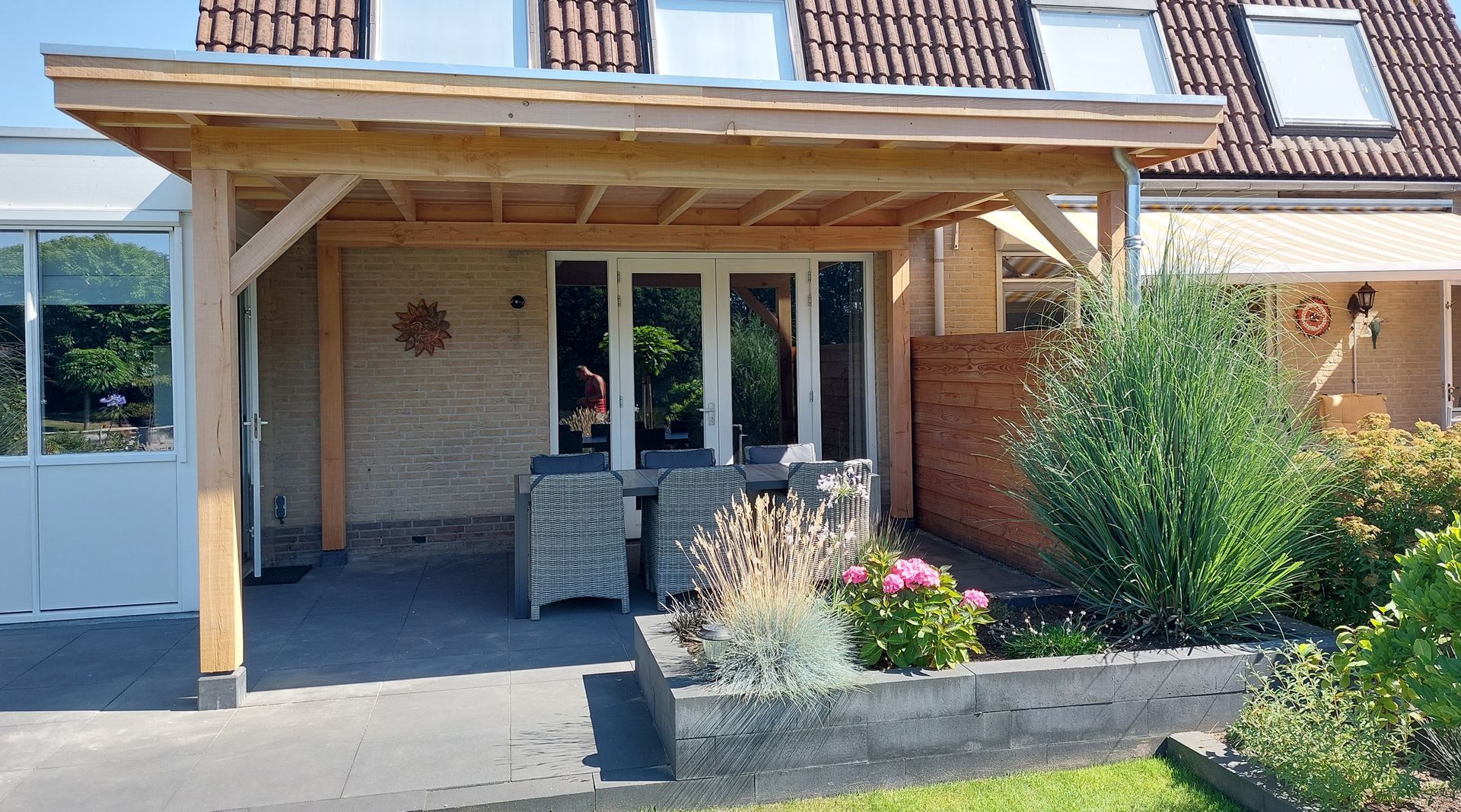 Een huis met een houten veranda en een tafel en stoelen ervoor