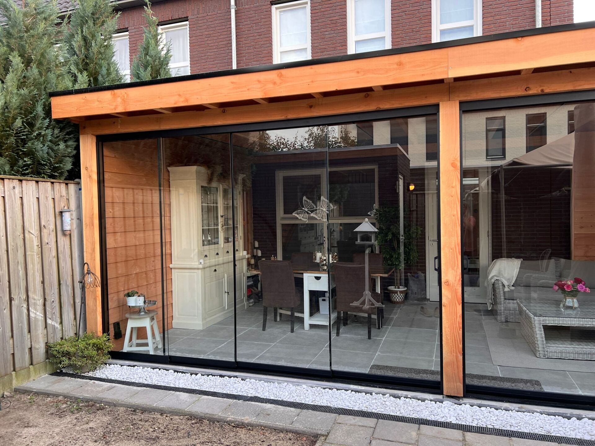 Een houten constructie met glazen schuifdeuren die naar een patio leiden.