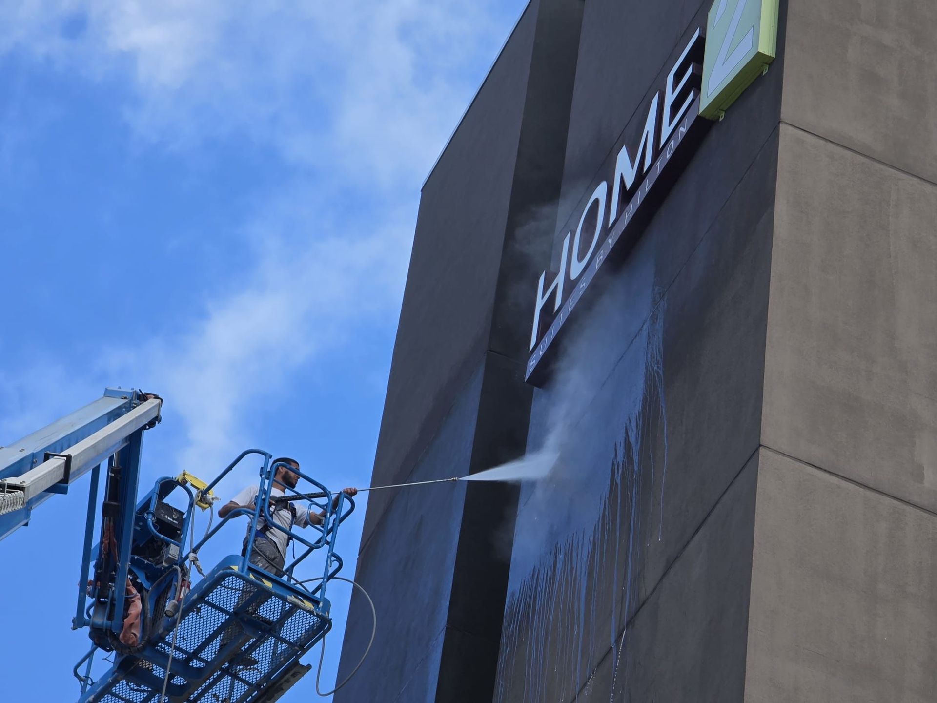 A man is cleaning a home sign on a building