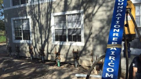 Blue lift arm beside beige house with two windows and tree shadows on the wall