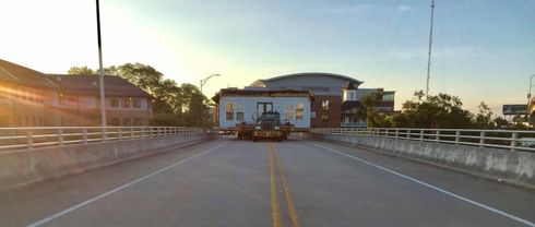 Empty road leading to a building at sunset, with white railings on both sides.