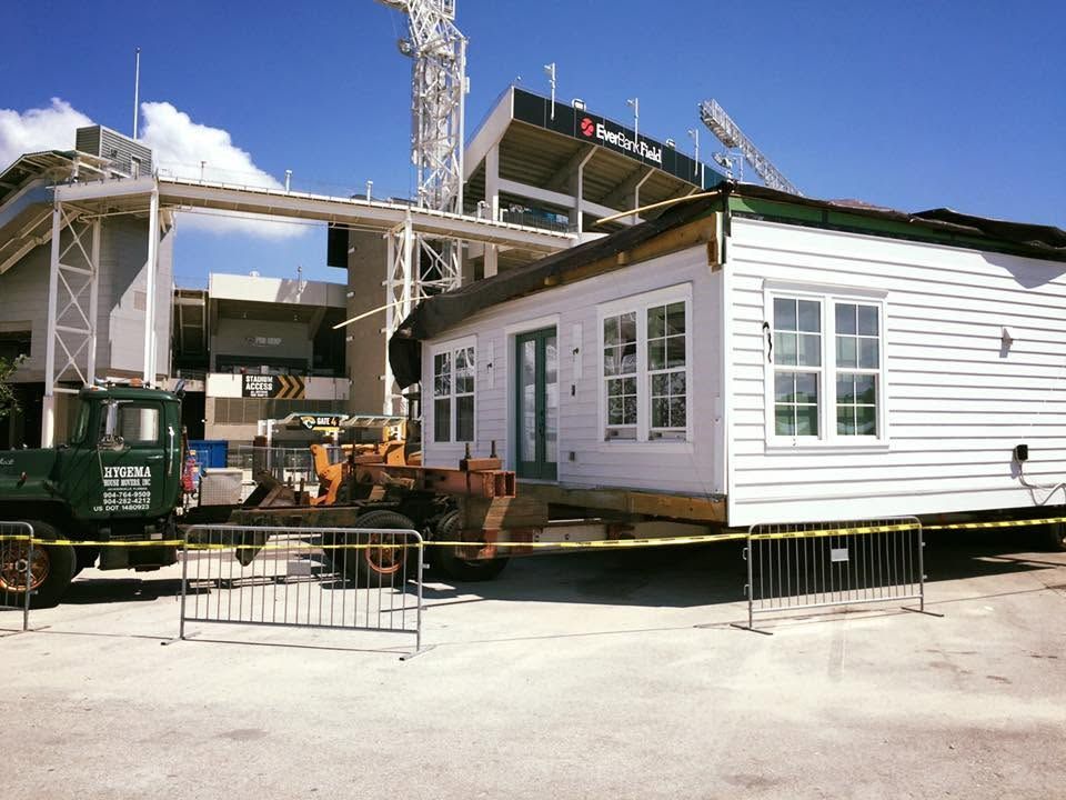 Construction site with a white building module, crane, and machinery under a clear blue sky