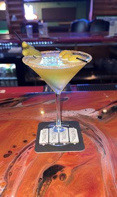 Cocktail in a martini glass with a lemon twist on a wooden bar top