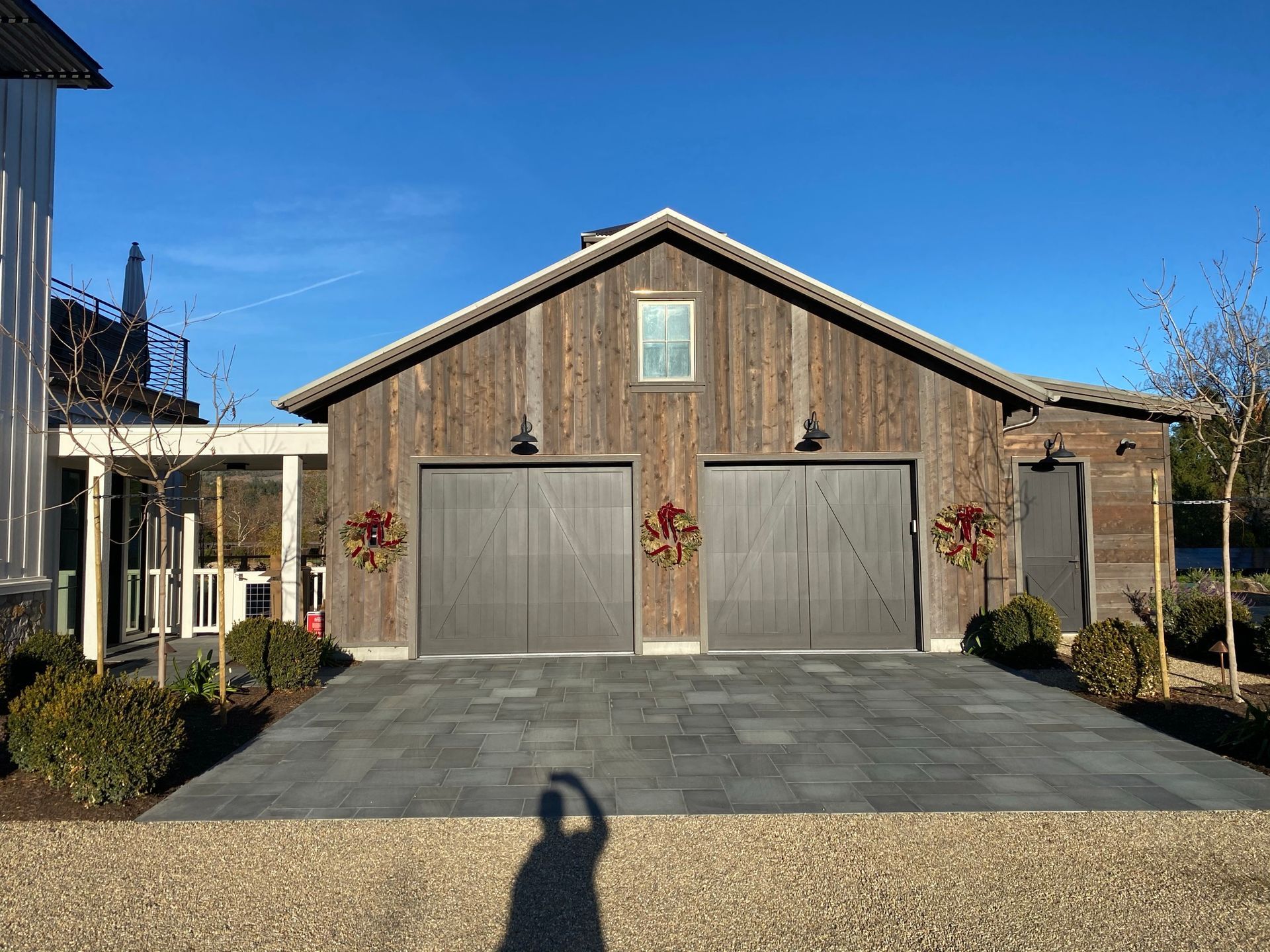 A light-gray corrugated metal building with two white garage doors, two small windows, and a central vent above.