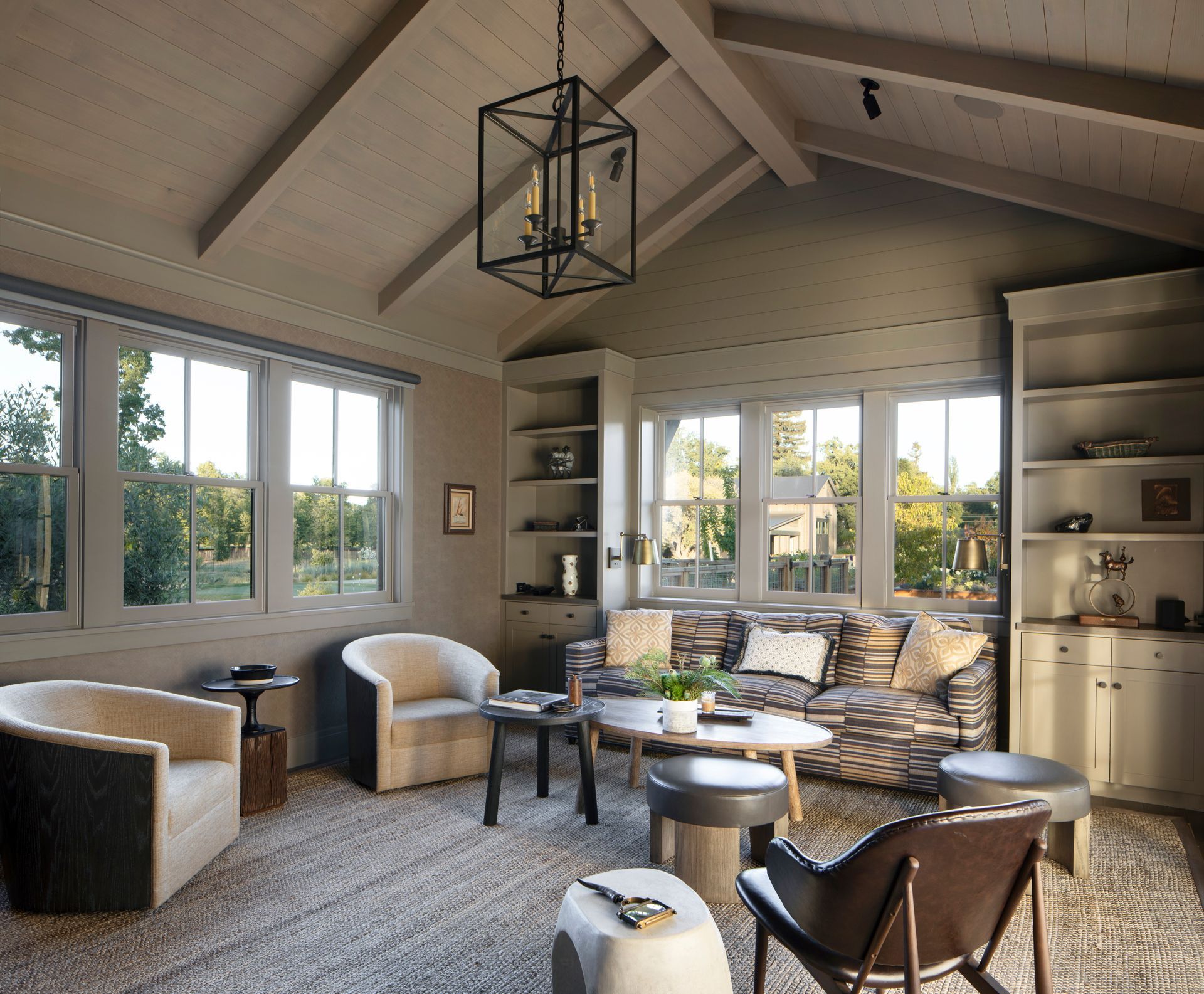 Cozy living room with neutral tones, windows, and a mix of seating, including armchairs and a sofa, under a sloped ceiling built by Nunley Custom Homes in Greenville, SC.
