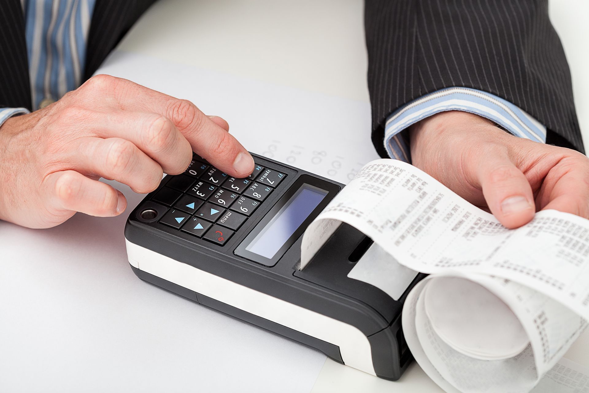 Hands using a card payment terminal with a printed receipt in a business setting