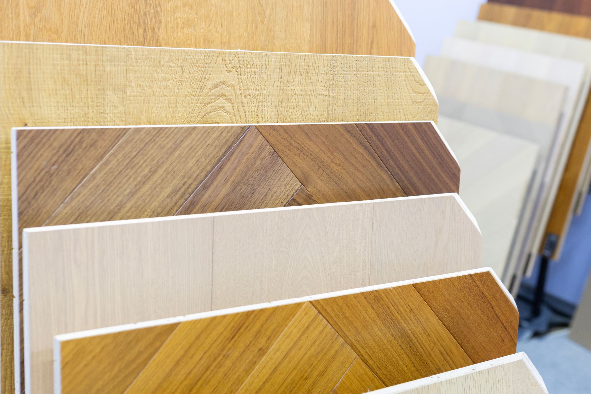 Display of assorted wood flooring samples in various tones and patterns arranged on angled showroom racks. Display of assorted wood flooring samples in various tones and patterns arranged on angled showroom racks.