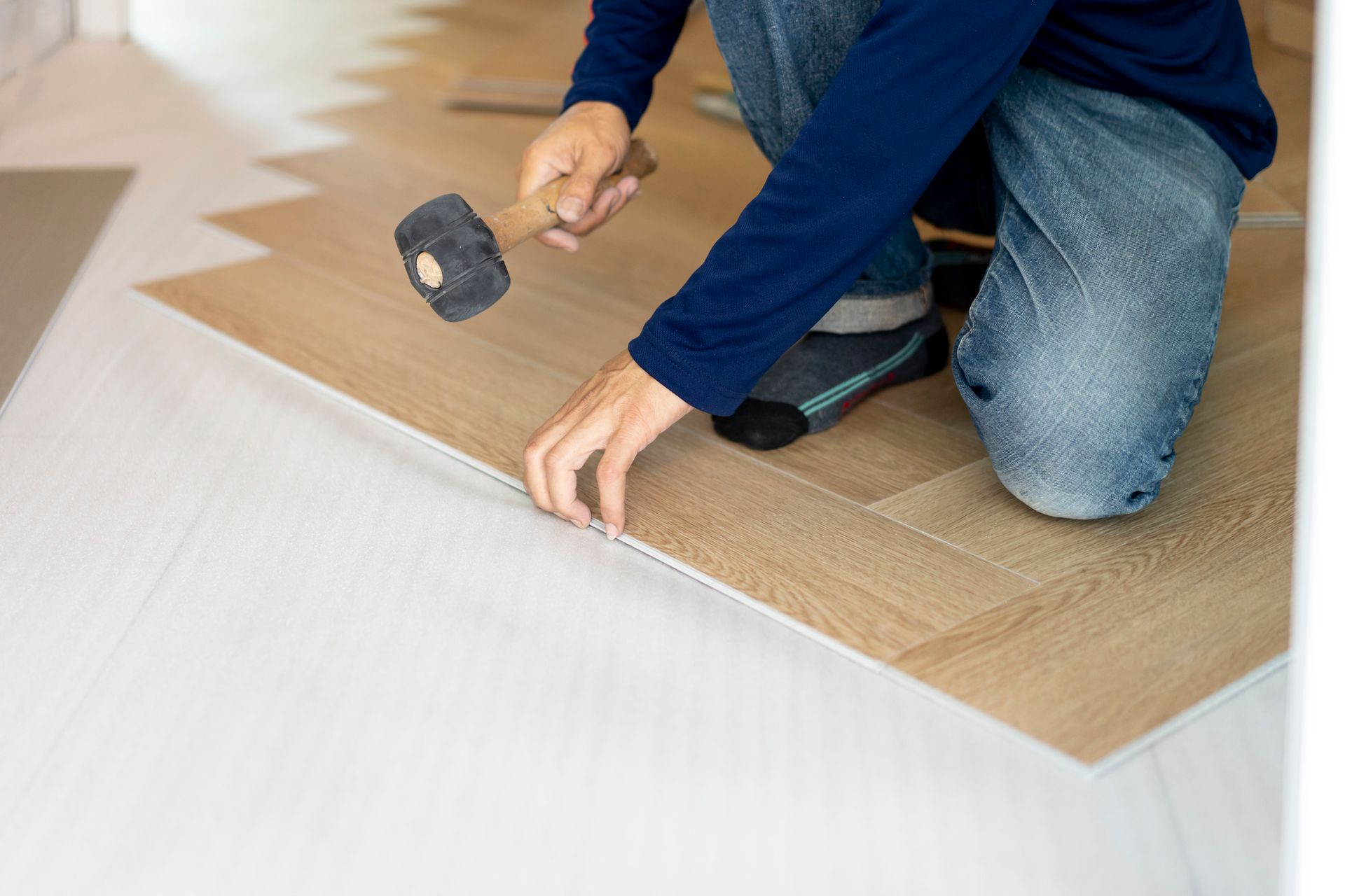 Contractor using mallet to install the parquet floor, showcasing excellent wood flooring