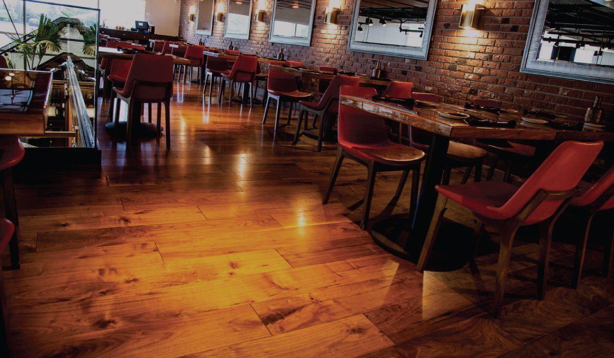 Restaurant interior with red chairs, wooden tables, and exposed brick walls.
