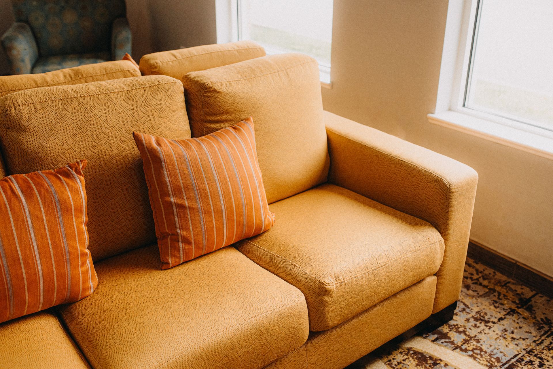 Mustard yellow sofa with striped pillows in a sunlit living room with upholstered decor. Mustard yellow sofa with striped pillows in a sunlit living room with upholstered decor.