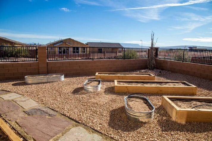 A row of wooden raised garden beds in a backyard.