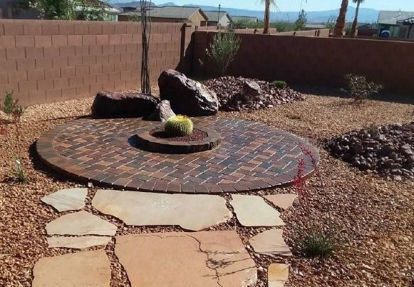 A brick patio with a fire pit in the middle of it